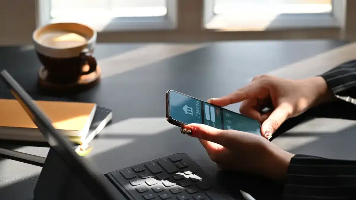 Femeie efectuând o tranzacție financiară online de pe smartphone la birou