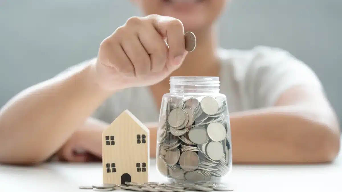 Femeie punând monede într-un borcan de economii pentru fondul de urgență