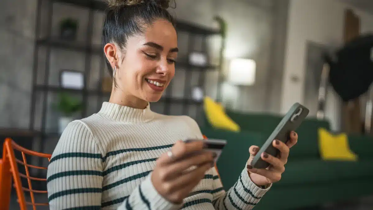 Tânără folosind cardul bancar și telefonul pentru plăți online