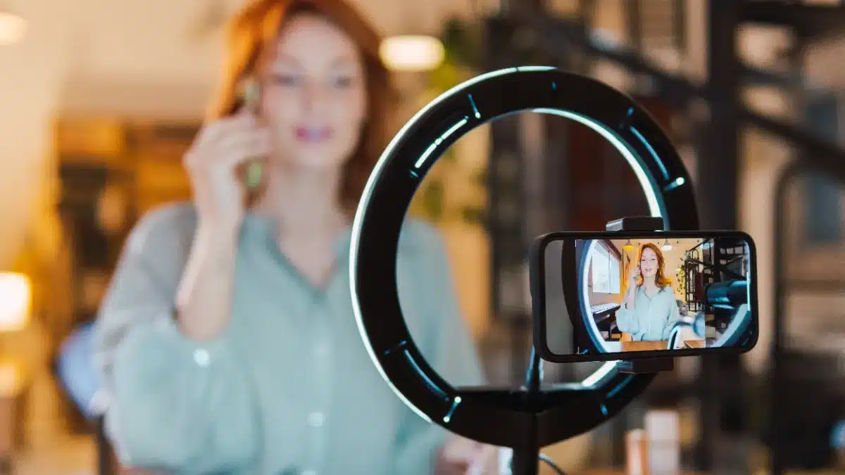Model de videochat creează conținut pentru social media cu telefonul și lumină de inel