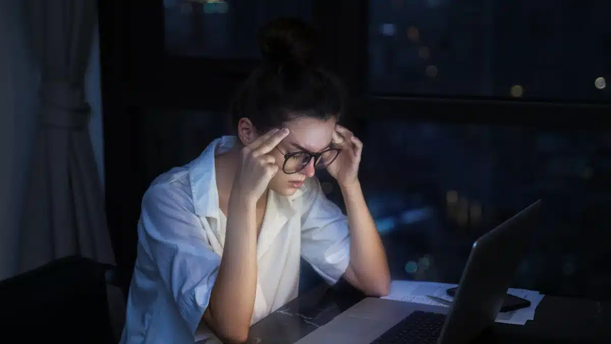 Tânără lucrând seara la laptop, aliniată la fusul orar al publicului internațional