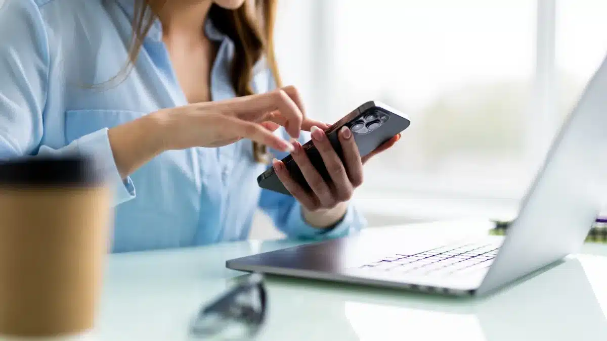 Tânără profesionistă la birou, cu laptop și telefon, într-un rol de marketing