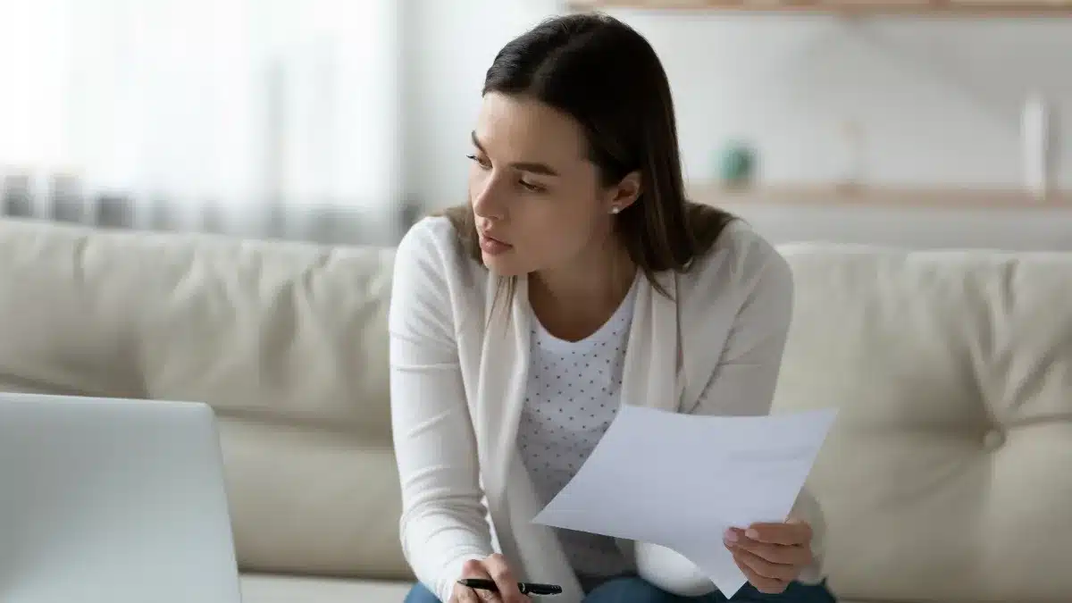 Tânără își gestionează bugetul personal la laptop, comparând un salariu fix cu venituri variabile din videochat