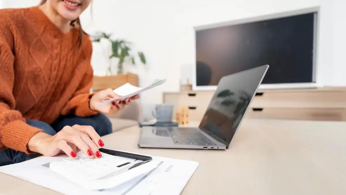 Tânără calculează veniturile lunare cu un calculator, comparând câștigurile din videochat cu salariul mediu