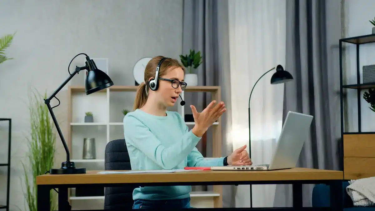 Tânără cu căști în conversație video relaxată, păstrând limitele profesionale