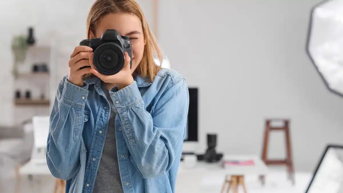 Femeie tânără ținând o cameră foto profesională într-un studio luminos