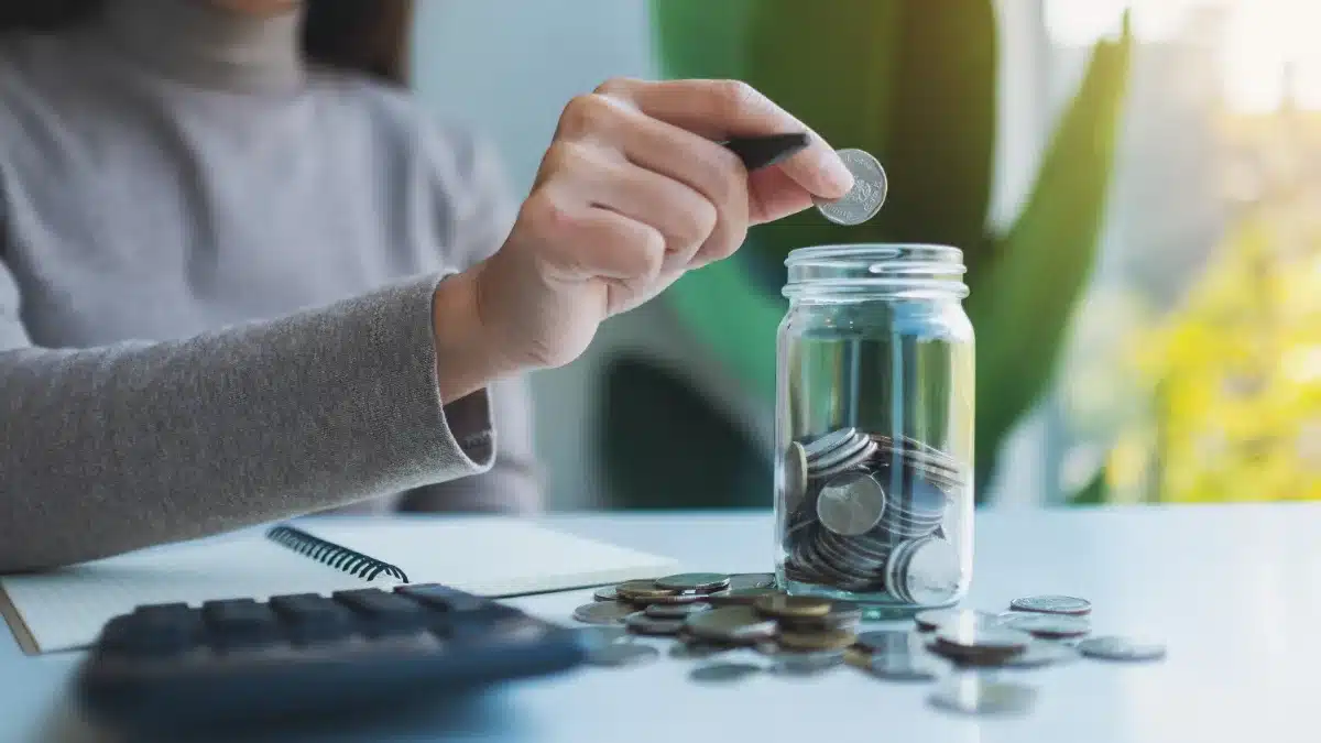 Monede puse într-un borcan de sticlă lângă un calculator — economii din veniturile de videochat